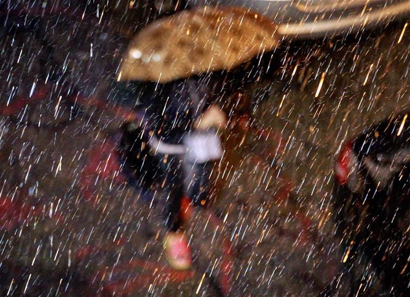 A Lebanese woman takes shelter under her umbrella as she walks in downtown...