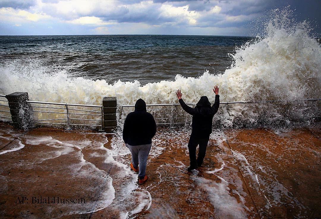 Lebanese men watch waves break at the Corniche wall, in Beirut, Lebanon,...