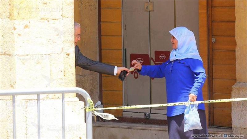 MP Ammar Houry, giving 10,000 L.L. to a woman, after a demonstration against the extension of terms for members of the parliament happened in the same area, in Beirut, Lebanon. (Hussien Baydoun / Alaraby Aljadeed)