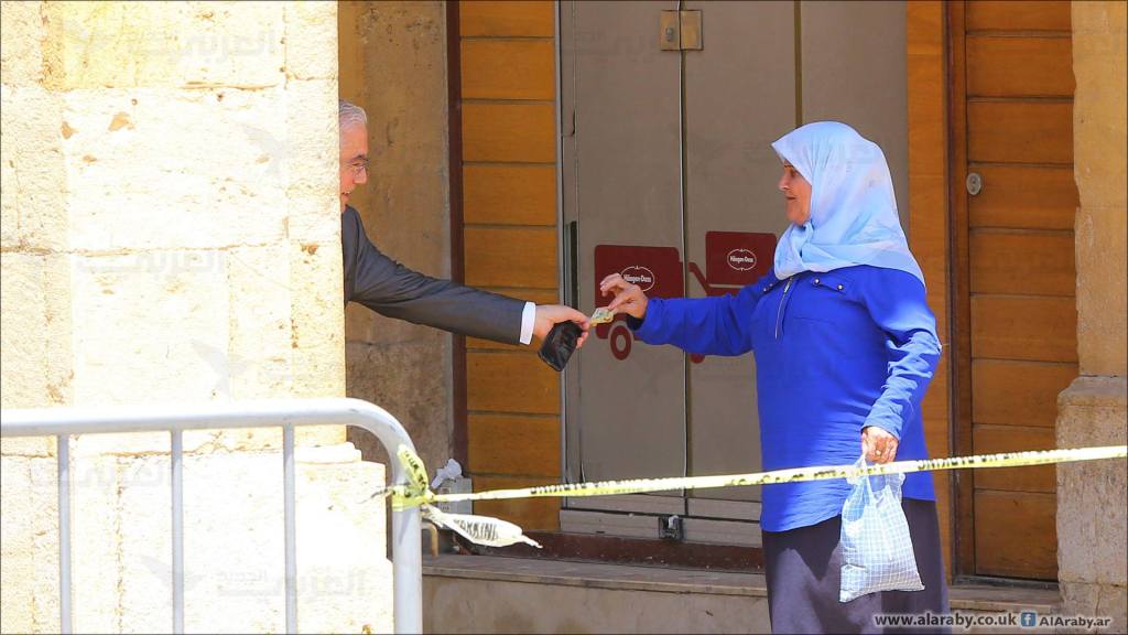 MP Ammar Houry, giving 10,000 L.L. to a woman, after a demonstration against the extension of terms for members of the parliament happened in the same area, in Beirut, Lebanon. (Hussien Baydoun / Alaraby Aljadeed)