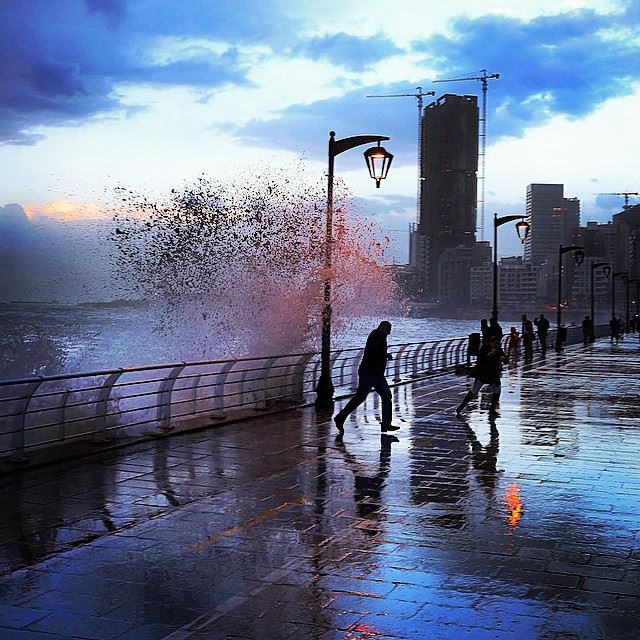 People watch high waves crashing on the seafront, at the corniche in...