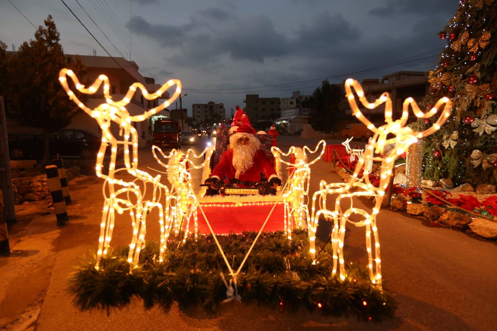 Santa Claus rides a Christmas decorated vehicle in Jiyeh. 