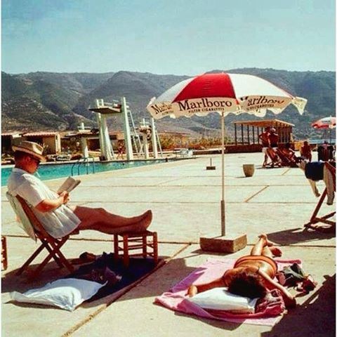 Tabarja - 1965 , Sun bathing leisure never changed, but the mountains behind have been invaded with concrete buildings .